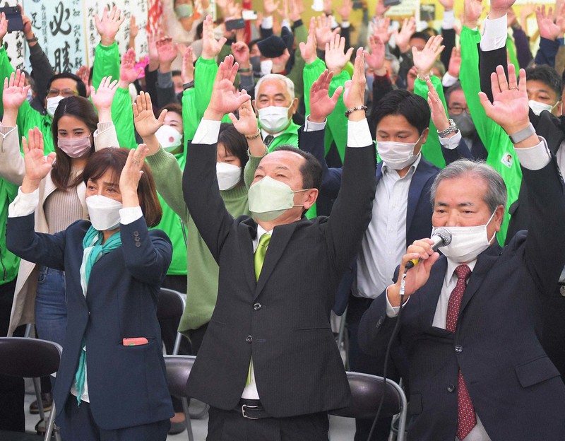 名護市長選で再選確実となり万歳する渡具知武豊氏(中央)=沖縄県名護市で2022年1月23日午後10時6分、津村豊和撮影
