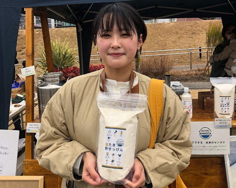 新たなデザインとなった「釜たき粉せっけん」を持つ恒松詩南さん=滋賀県草津市の草津川跡地公園de愛ひろばで