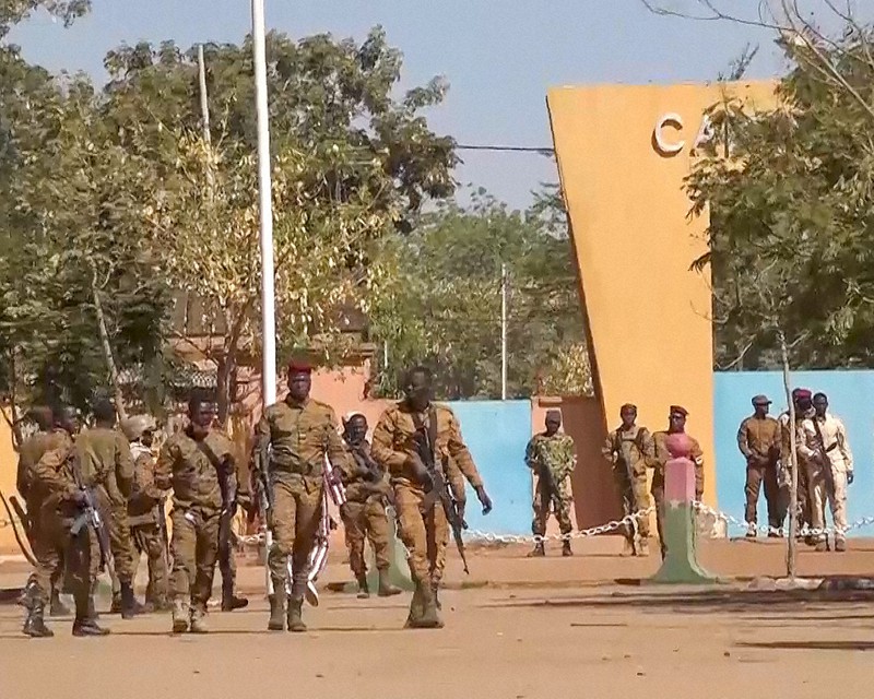 クーデターが起きたブルキナファソの首都ワガドゥグで、軍の駐屯地前を歩く兵士ら=24日、AP