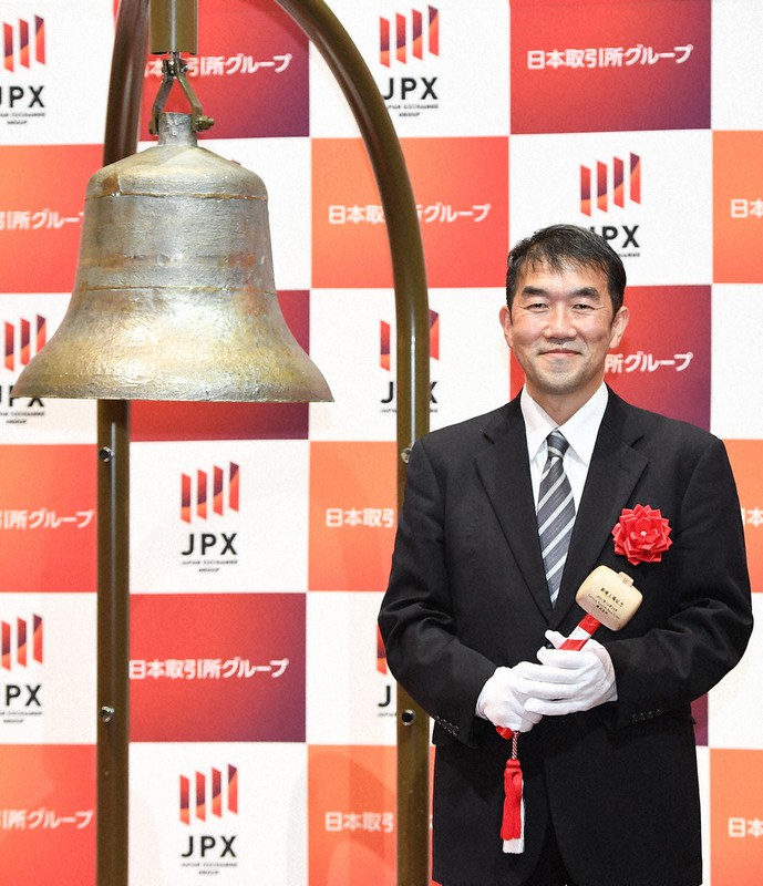 マザーズに上場し、セレモニーで鐘の横で写真に納まるグリーンアースインスティテュートの伊原智人社長=東京都中央区の東京証券取引所で2021年12月24日、前田梨里子撮影