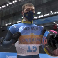 「NO　WAR　IN　UKRAINE」と書かれたボードを競技中継用テレビカメラに示したウクライナのウラジスラフ・ヘラスケビッチ選手＝2022年2月11日、NBC提供・AP