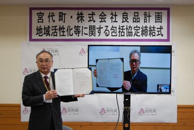 協定書にサインした新井康之町長（左）とモニター画面に映る堂前宣夫社長＝埼玉県宮代町役場で2022年2月10日、古賀三男撮影