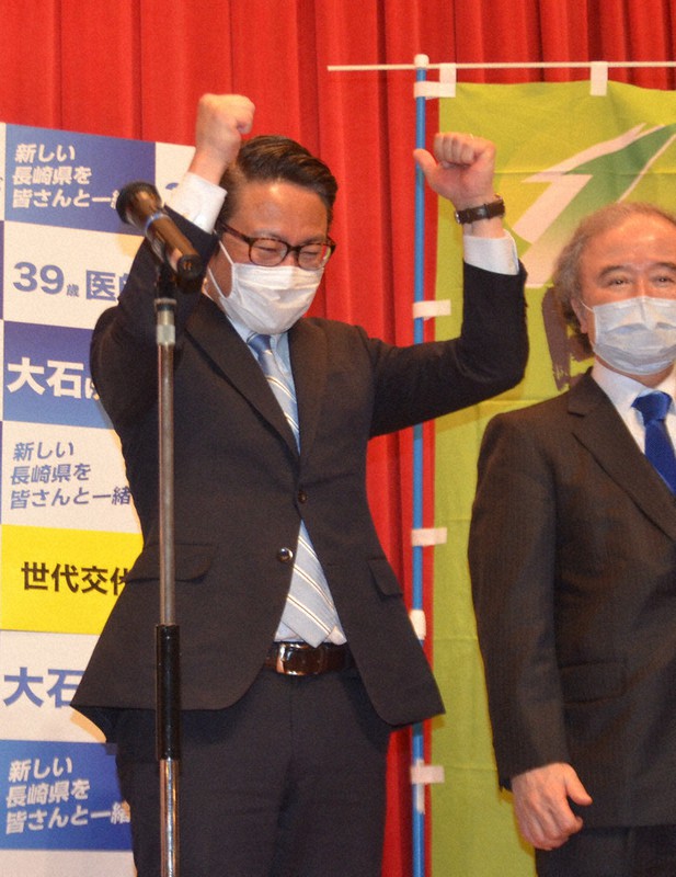 当選確実の知らせを受けてガッツポーズする大石氏(左)