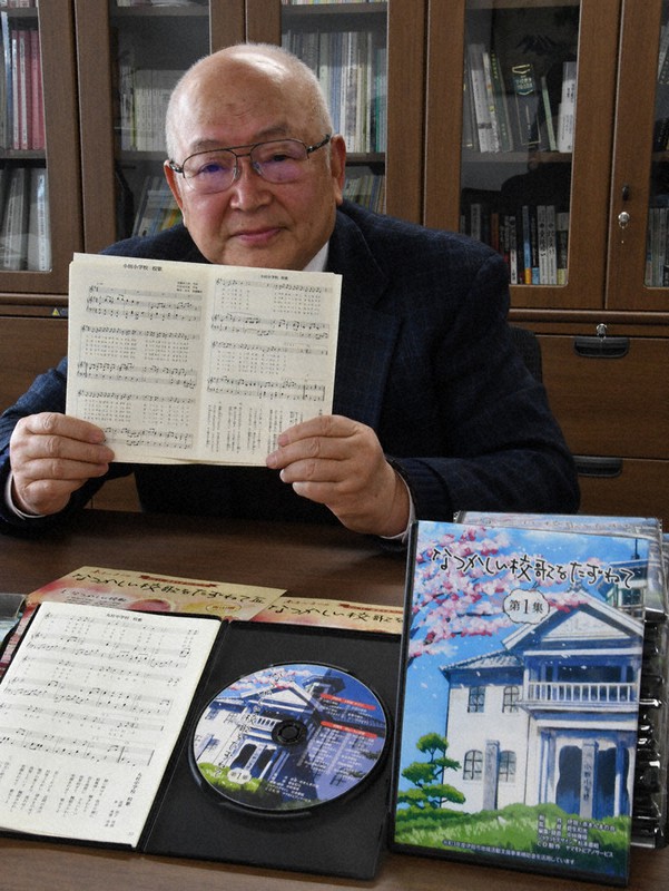 「なつかしい校歌をたずねて・第1集」の小田小を描いたケース、CDと歌詞、楽譜の冊子を手にする菅生和光さん=三重県伊賀市役所で、2022年2月24日午前10時54分