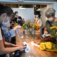 花農家から届いた生花を、来場者が持ち帰りしやすいよう小分けの花束にするスタッフたち＝東京都台東区で2021年7月10日午前10時、塩田彩撮影