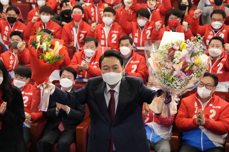 韓国大統領選挙で当選し、花束を持って喜ぶ保守系最大野党「国民の力」の尹錫悦氏=ソウルで2022年3月10日、AP