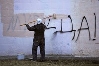 A worker paints over graffiti saying 'Yes to Peace!' on a wall of an apartment building in St. Petersburg, Russia, on March 18, 2022. (AP Photo)