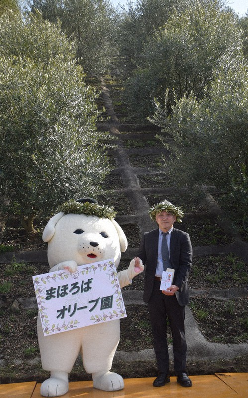オリーブの木の前で、町のゆるキャラ「雪丸」と並ぶ藤井さん=王寺町で2022年3月15日午後3時18分、熊谷仁志撮影