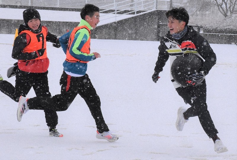 雪の中、子どもたちとタグラグビーを楽しむ田母神一喜さん(右)=福島県鏡石町鳥見山陸上競技場で2021年12月18日午前9時37分、磯貝映奈撮影