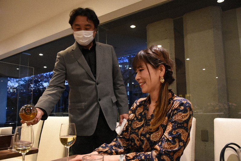 ウクライナワインをイベント参加者に提供する斎藤社長(左)=横浜市中区末吉町4のグリルエトナ伊勢佐木町店で、2022年4月1日午後6時22分、秋丸生帆撮影