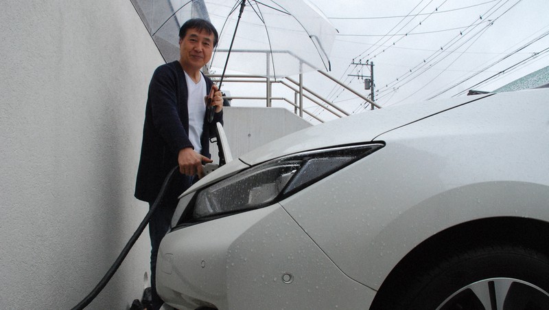昼間の太陽光で発電した電力を日産リーフに充電し、夜間は自宅に戻して使うという飯田哲也さん=横浜市内で2022年3月、川口雅浩撮影