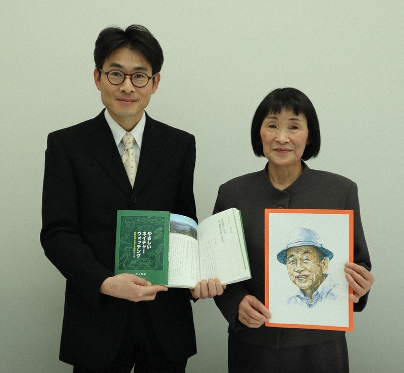 「自然の案内人」村上宣雄さんの肖像画(画・藤腹守男さん)を手にする妻尚子さん(右)と、出版された遺作本を持つ長男悟さん=滋賀長浜市役所で、長谷川隆広撮影