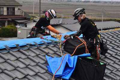 地震で破損した屋根瓦にブルーシートをかけるボランティアら＝宮城県山元町で2022年4月13日、平家勇大撮影