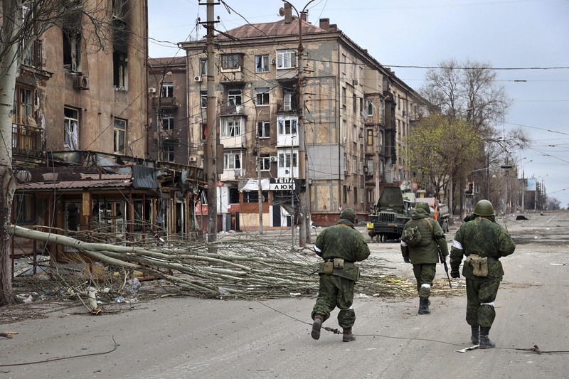 破壊された建物の前を歩く親ロシア派勢力の兵士ら=ウクライナ・マリウポリで2022年4月16日、AP