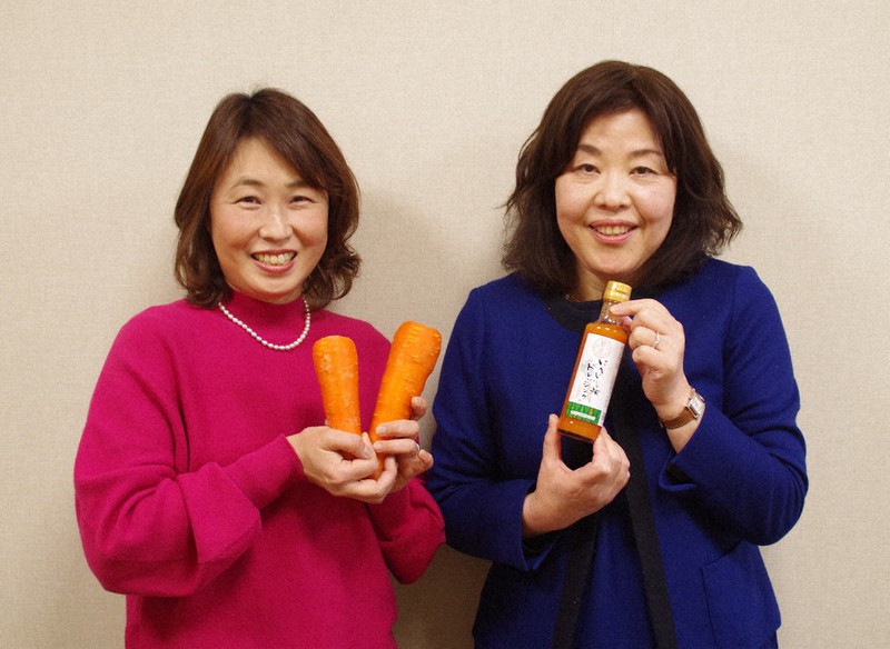 新座市産ニンジンを手にする十文字学園女子大の曽矢麻理子助手(左)とドレッシングを手にする小林三智子教授=埼玉県新座市で2022年2月1日、山越峰一郎撮影