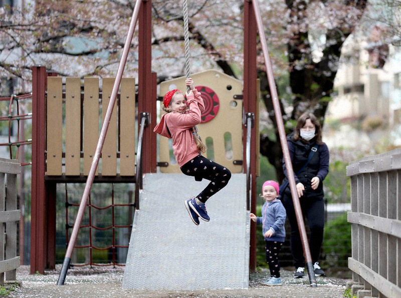 公園で遊ぶ(左から)ミロスラバさん、ブラディスラバさん、母のナタリアさん。夫のセルギーさんは、ウクライナ国内にとどまり地域防衛隊として街を守っている。ナタリアさんは「日本の桜はきれい。でもウクライナを思うと複雑な気持ち」と話した=東京都港区で5日