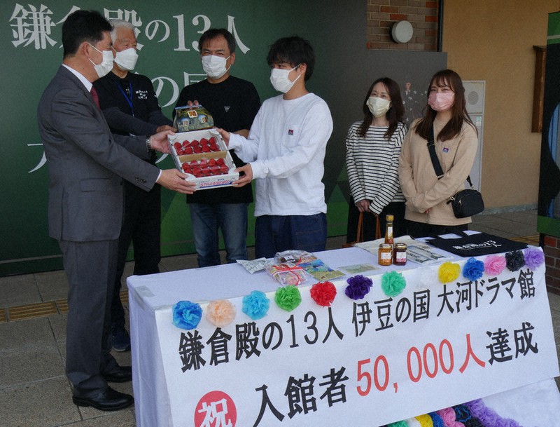 5万人目となり、記念品を受け取る内田さん一家(右側の4人)=静岡県伊豆の国市四日町で2022年4月23日、長沢英次撮影