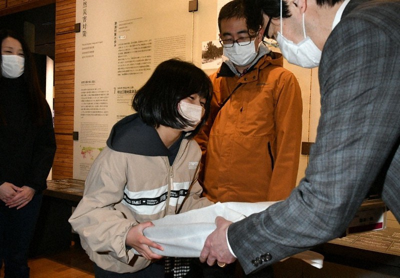 50万人到達の記念品を受け取る小林弘典さん(右から2人目)の長女、奈央さん=岩手県陸前高田市の東日本大震災津波伝承館で2022年4月30日、奥田伸一撮影