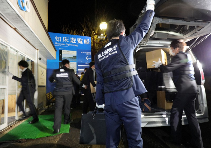 家宅捜索に入った「知床遊覧船」の事務所(左)から押収した資料などが入った段ボールを運び出す海上保安庁の職員ら=北海道斜里町で2022年5月2日午後8時3分、貝塚太一撮影