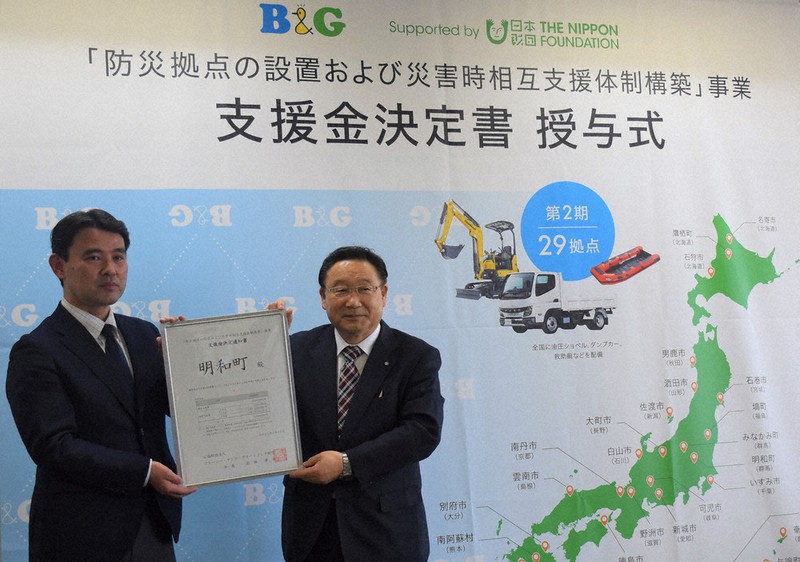 B&G財団の支援金決定書を手にする明和町の冨塚基輔町長(右)=群馬県明和町役場で2022年4月11日、上鵜瀬浄撮影