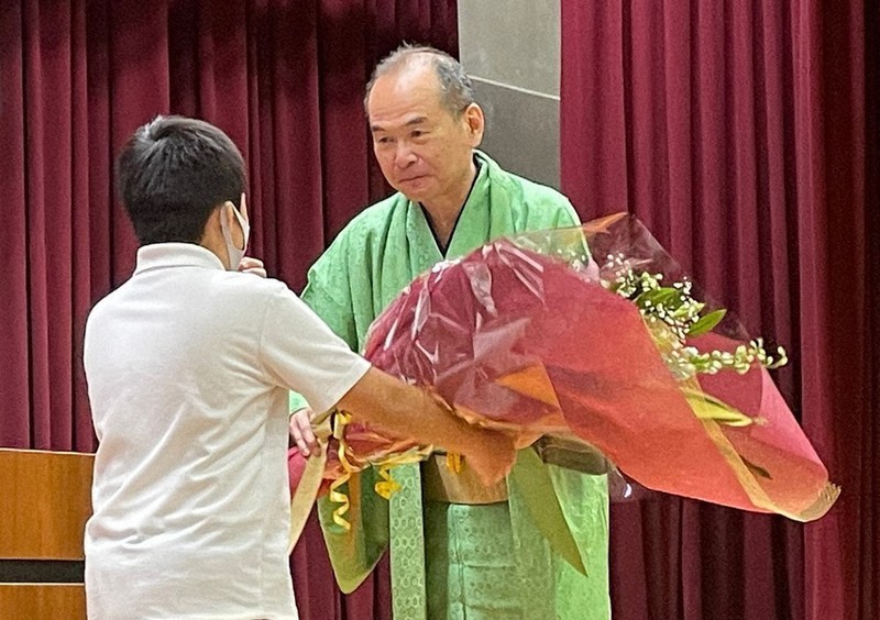 小学生代表から花束を受け取る笑福亭仁智さん=大阪府羽曳野市郡戸の市立丹比小学校で2022年5月12日午前10時4分、玉木達也撮影