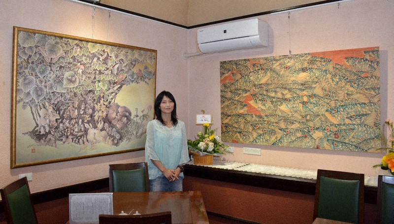 半年がかりで制作したというヒノキ板をキャンバスにしたボールペン細密画(右)と作者の浩而魅諭さん=札幌市西区で2022年5月11日、安味伸一撮影