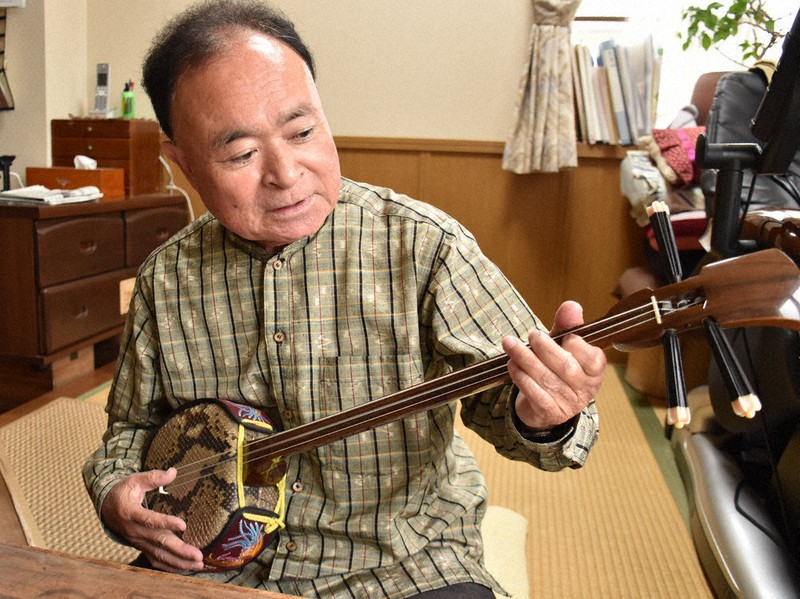 1970年に沖縄から岐阜に移住する際に持って来た愛用の三線を奏でる大城豊次さん。音色を聞くと、今でも癒やされる=岐阜市で