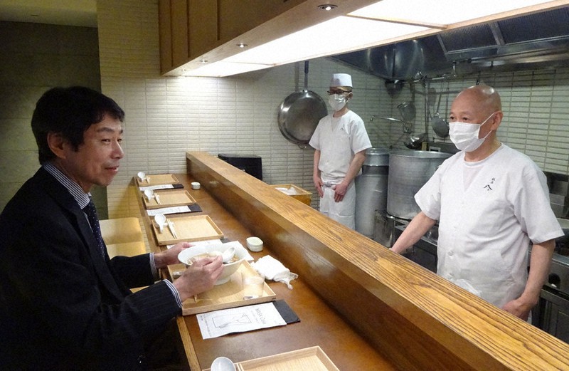 ラーメン店への聞き取り調査の際に試食する「ラーメン議連」事務局長の高木宏寿衆院議員(左)=東京都中央区で4月26日