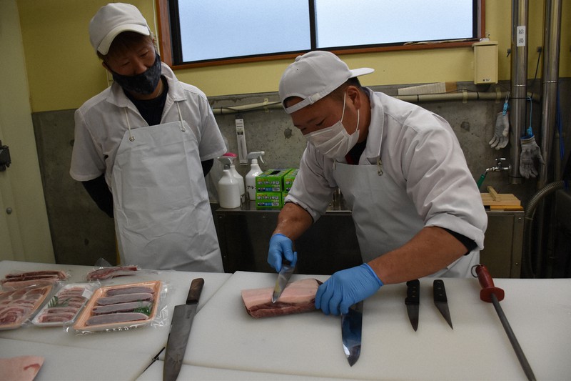 5種類の包丁を使い分け、イノシシ肉を切り分ける高沢さん(右)=栃木県那珂川町和見の町イノシシ肉加工施設で2022年4月26日午後2時34分、渡辺佳奈子撮影