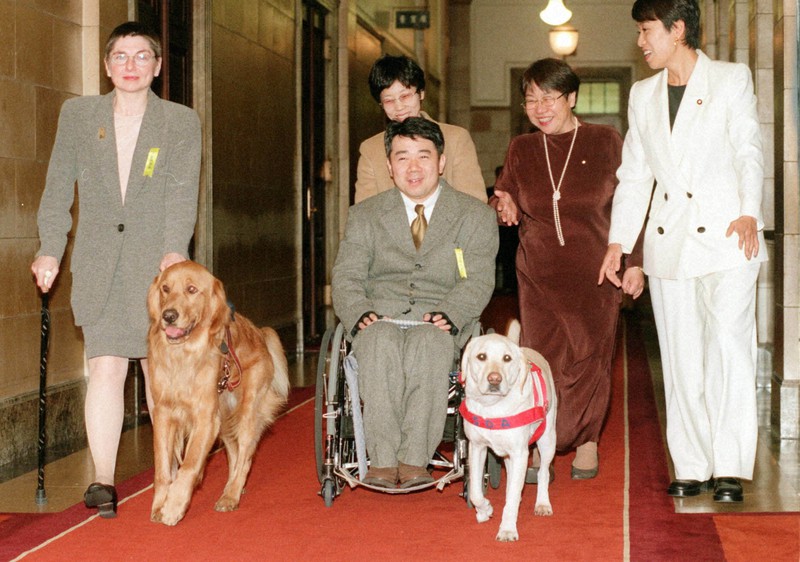 衆院予算委の傍聴のため、介助犬シンシアとともに委員会室に向かう木村佳友さん(中央)ら=国会で1999年2月1日午後3時38分、加古信志撮影