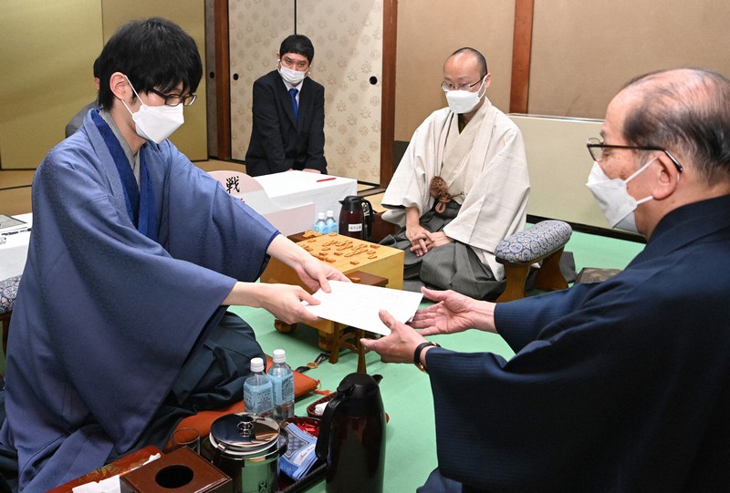 第80期名人戦七番勝負第4局で、立会の桐山清澄九段(手前右)に封じ手を渡す斎藤慎太郎八段(同左)。奥右は渡辺明名人=山口市の山水園で2022年5月19日午後6時37分、徳野仁子撮影