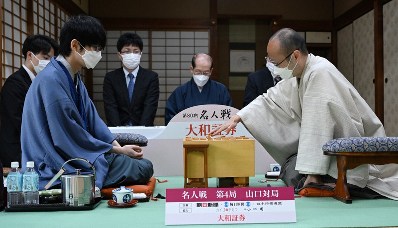 第80期名人戦七番勝負第4局2日目、挑戦者の斎藤慎太郎八段(手前左)の封じ手を受け、一手を指す渡辺明名人(同右)。中央奥は立会の桐山清澄九段=山口市の山水園で2022年5月20日午前9時2分、岩下幸一郎撮影