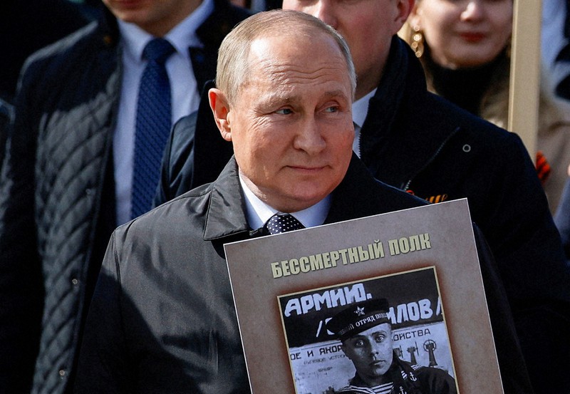 父親の写真を手に、対ドイツ戦勝記念日の式典に出席したロシアのプーチン大統領=モスクワで2022年5月9日、ロイター