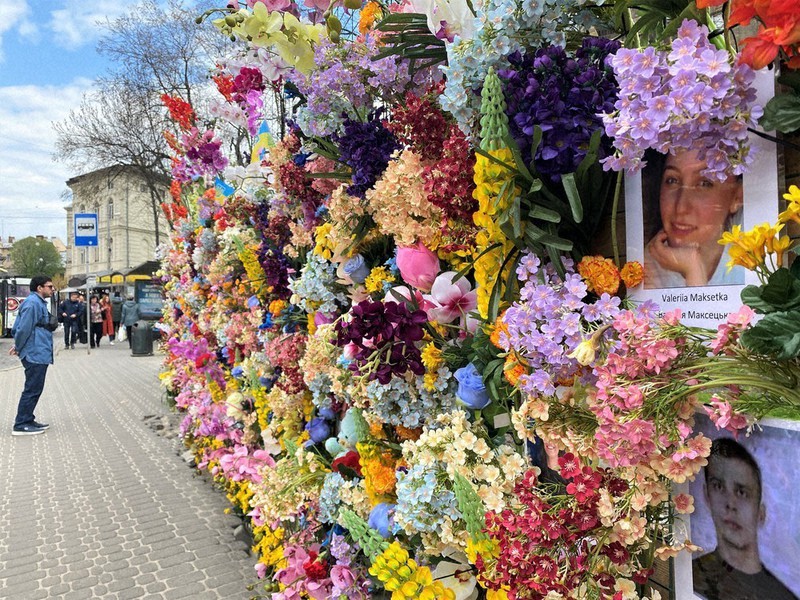 ロシア軍の侵攻による犠牲者を悼む壁。一人一人の顔写真と名前がたくさんの造花に埋もれるように掲示されている=ウクライナ西部リビウ中心部で2022年4月30日午後2時50分、真野森作撮影