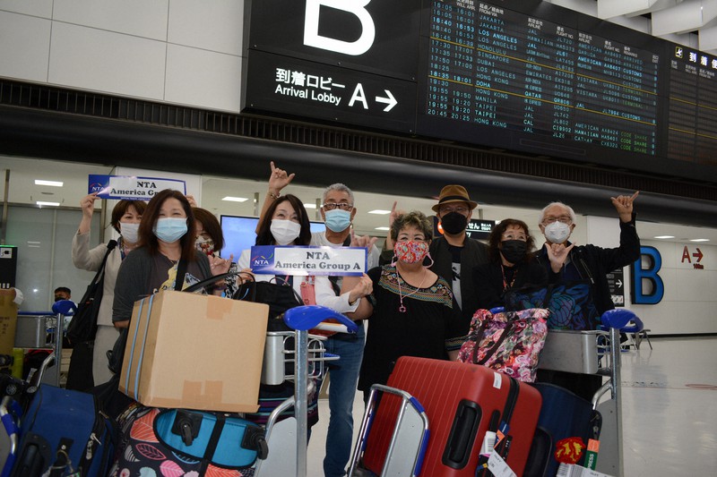 成田空港に到着し、出迎えの添乗員と一緒にポーズを取る米国からのツアー参加者=千葉県成田市で2022年5月24日午後7時4分、中村宰和撮影