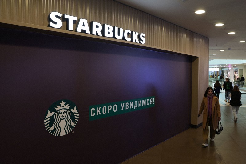 閉店したスターバックスの前を通り過ぎる女性=ロシア西部サンクトペテルブルク市内で5月23日、ロイター