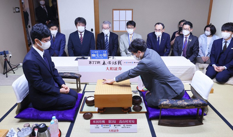 第77期本因坊決定戦七番勝負第3局が始まり、第1着を打つ本因坊文裕(右)。左は挑戦者の一力遼棋聖=長野県高山村の山田温泉「藤井荘」で2022年6月1日午前9時、長谷川直亮撮影