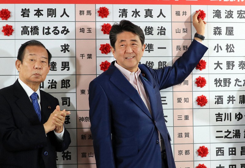 2019年参院選で当選確実となった候補者の名前に花をつける安倍晋三首相(当時)。この選挙では医療・福祉系団体候補8人が出馬し、激しいつばぜり合いを展開した=東京都千代田区で2019年7月21日午後9時56分、梅村直承撮影