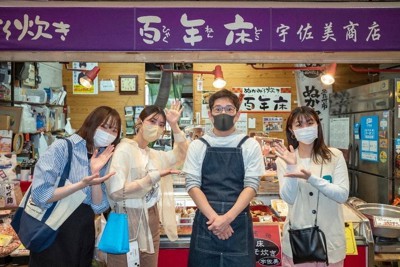 火災後に旦過市場を訪れ、店主（右から2人目）と記念撮影する西南女学院大の学生たち＝北九州市小倉北区で（同大提供）