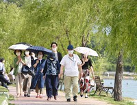 真夏日を記録する暑さとなり、日傘を差して水辺を散策する人たち＝福岡市中央区で2022年6月4日午後3時49分、徳野仁子撮影