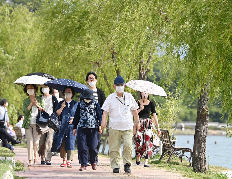 真夏日を記録する暑さとなり、日傘を差して水辺を散策する人たち=福岡市中央区で2022年6月4日午後3時49分、徳野仁子撮影