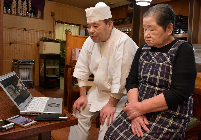 すし店を営む桑添正之さん(左)と母親の京子さん。自分たちと同様に行方不明になった家族を捜している川崎市の小川益宏さんとオンラインで会話を交わした=青森県三戸町で2021年11月28日午後3時28分、銭場裕司撮影