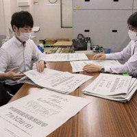 印刷された選挙公報を確認する選管の職員
