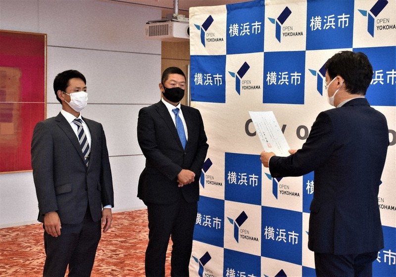 山中竹春市長(右)から推薦状を交付されるENEOSの大久保秀昭監督(中央)と川口凌主将=横浜市役所で2022年6月27日、牧野大輔撮影