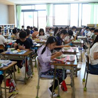対面で食事する子ども（左側）と対面を避ける児童（右側）。感染対策の考えの違いは子どもの間でも浮き彫りとなっている＝千葉県習志野市立谷津小学校で2022年5月30日、石川勝義撮影