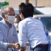 街頭演説に集まった人と握手をする候補者（右）＝静岡市葵区で2022年6月25日、深野麟之介撮影（画像の一部を加工しています）
