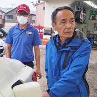 給油ノズルを握る鈴木さん（右）＝和歌山県串本町で、松田学撮影
