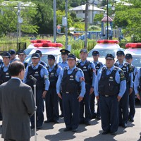 帰還困難区域の避難指示が一部で解除され、パトロールの出動式で吉田淳町長（手前）のあいさつを聞く警察官＝福島県大熊町で2022年6月30日午前9時1分、前田梨里子撮影