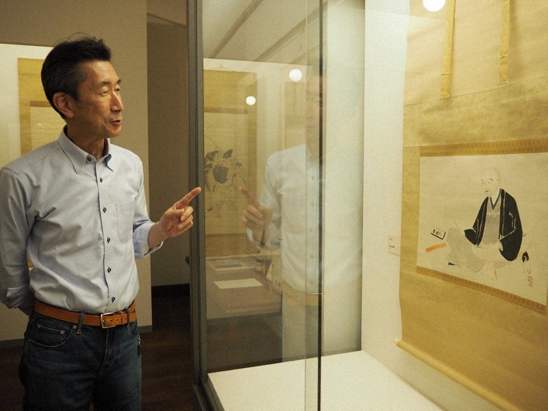 大阪商業大商業史博物館で開催中の「秘蔵の大阪画壇展」。北野恒富が描いた井原西鶴像を前に、作品の魅力について語る明尾圭造教授=同博物館で、山田夢留撮影