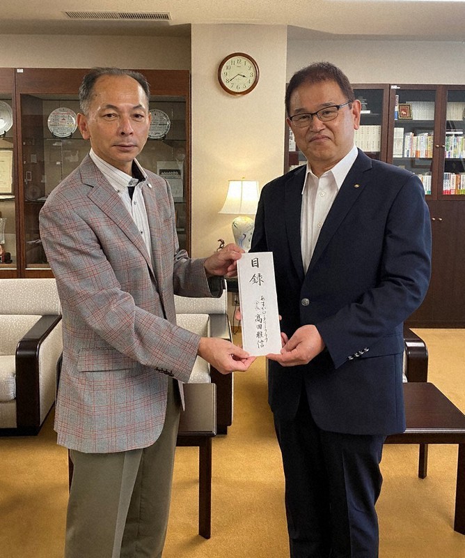 ウクライナからの留学生を支援するため、天理大の永尾教昭学長(左)に寄付金の目録を手渡すあすかRCの高田雅信会長=同RC提供